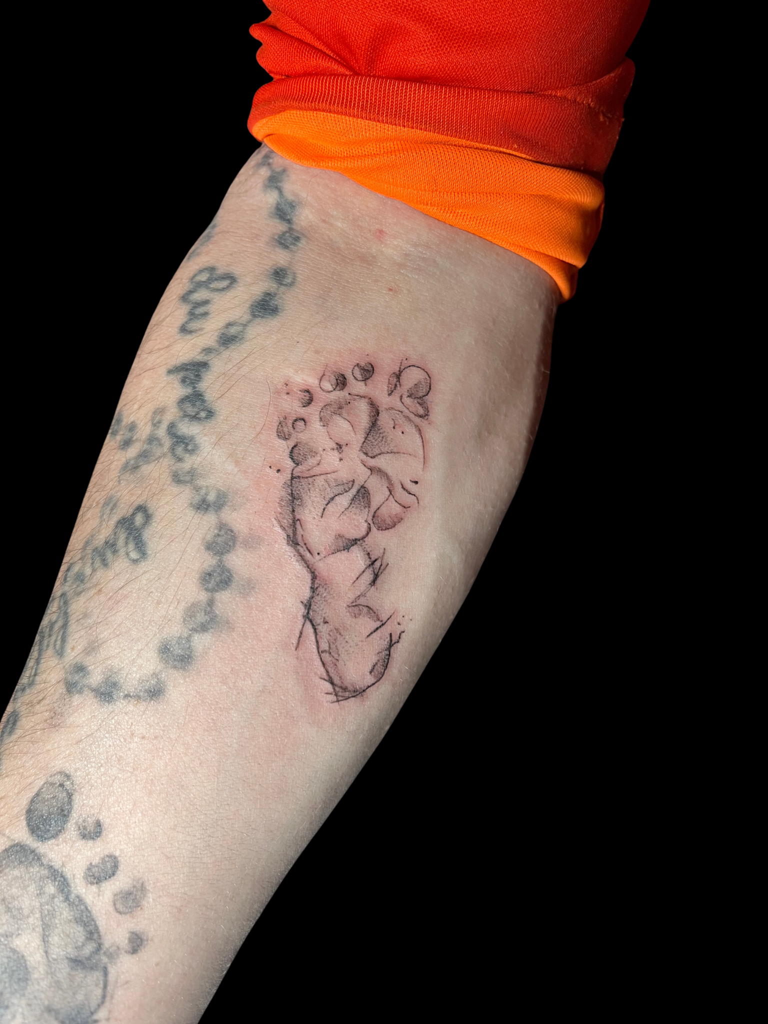 Tatouage empreinte de pied de bébé en fine ligne sur avant-bras — Akamoa Tattoo Moustiers-Sainte-Marie